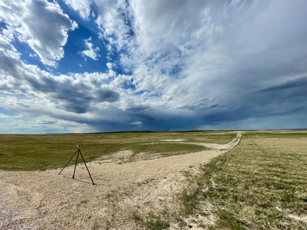 open landscape with dirt road, blue sky and dramatic clouds
