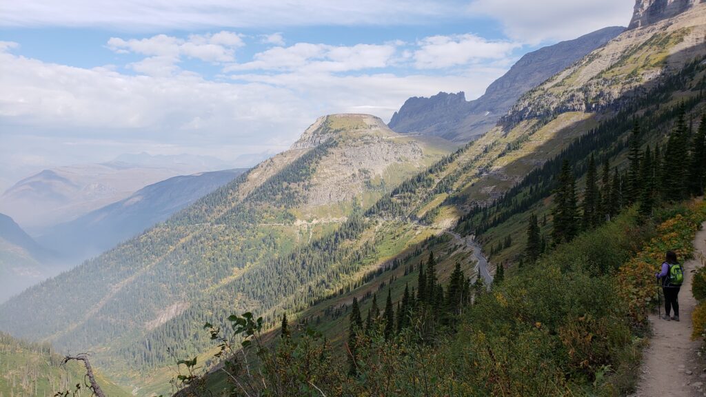 Hiker takes in expansive mountain view from the High Line Trail in Glacier National Park