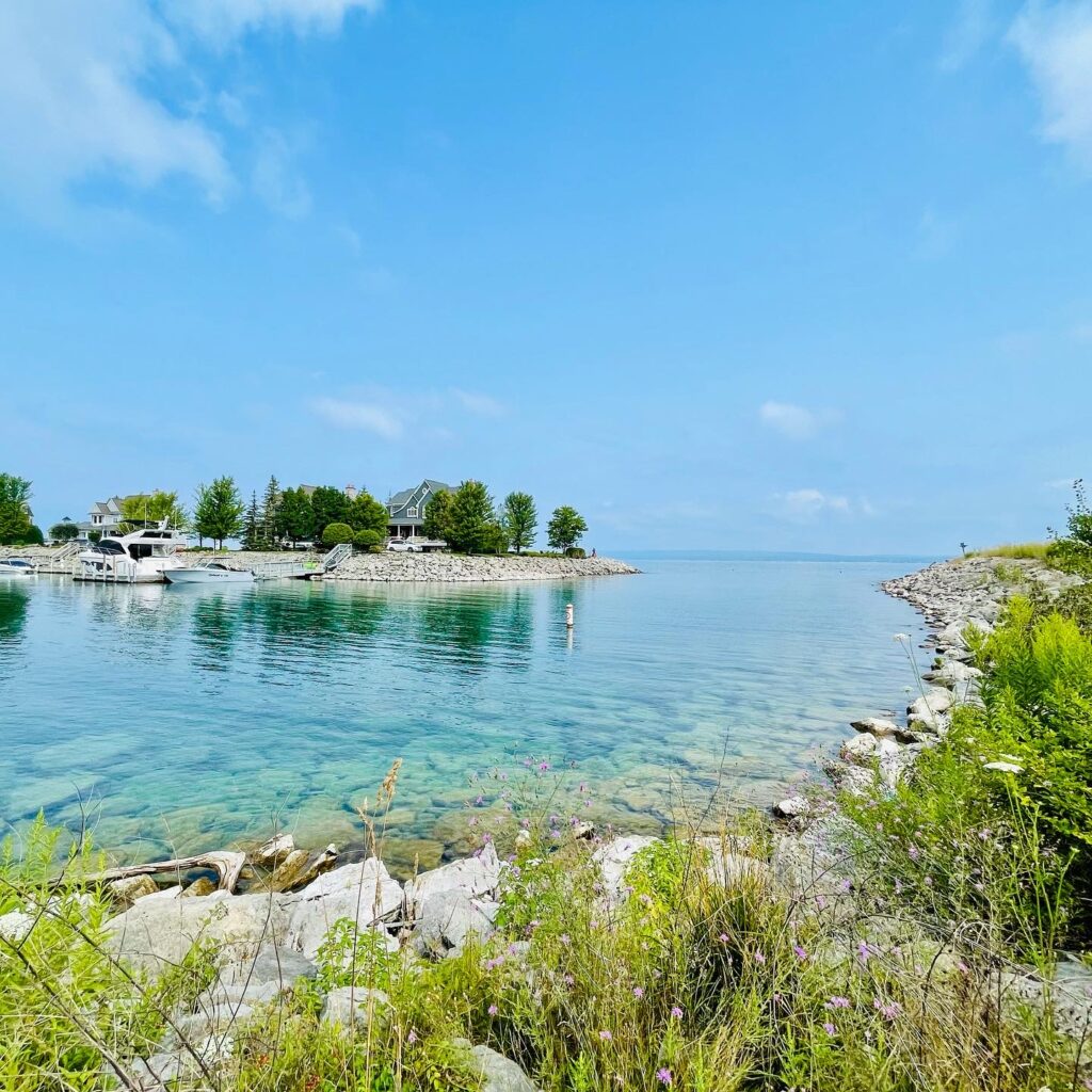 Lake Michigan along the shore line with rocks, grass, and clear water