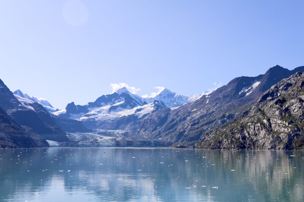 John's Hopkins glacier with icy water and mountains in the background with blue sky