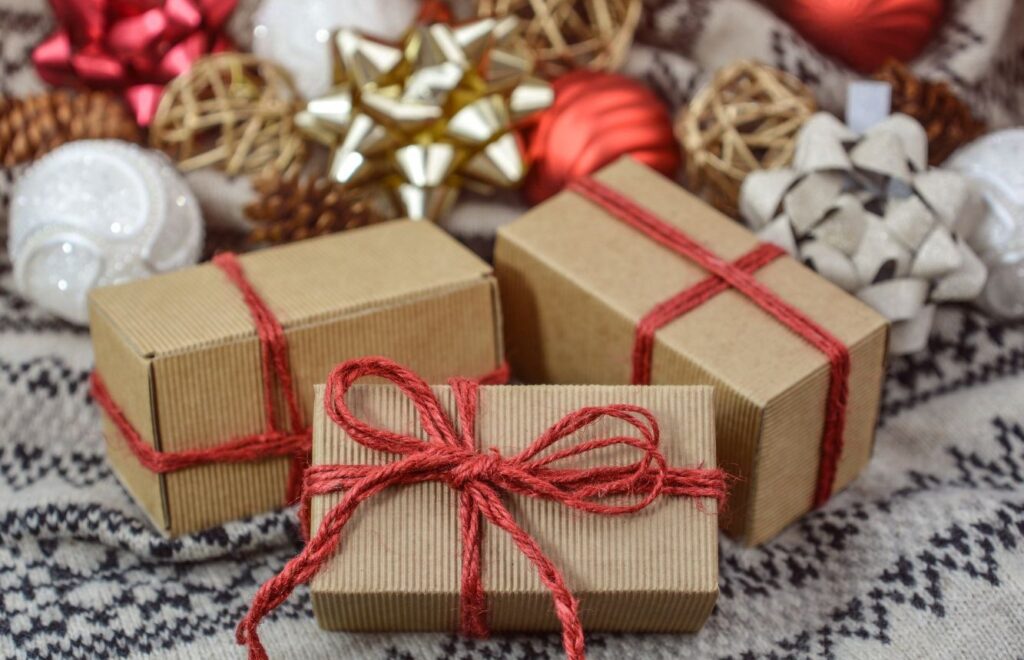 brown boxes with red ribbon in front of white and gold ornaments and bows
