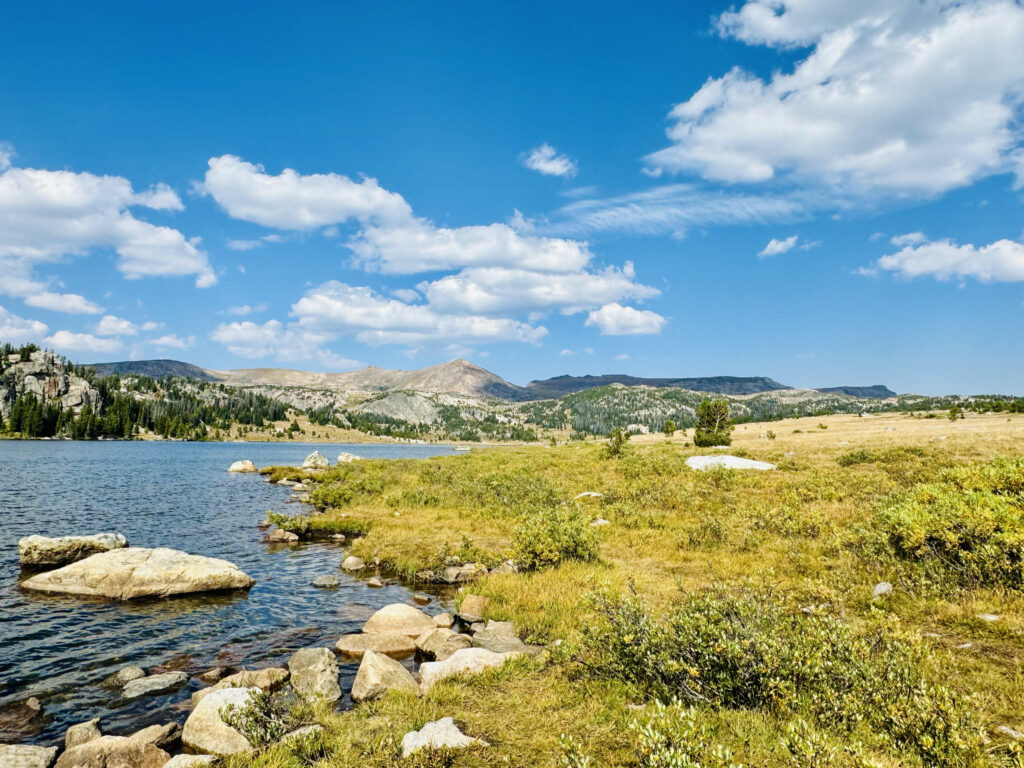 Vast mountain lake view with grass around and cloudy sky